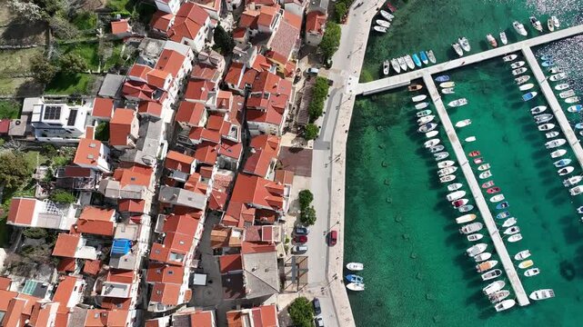 Baska beach and coastline with crystal-clear turquoise water, marina boats, city street, sunny summer mood captured from drone view on Krk Island. Baska vacations town in Adriatic sea