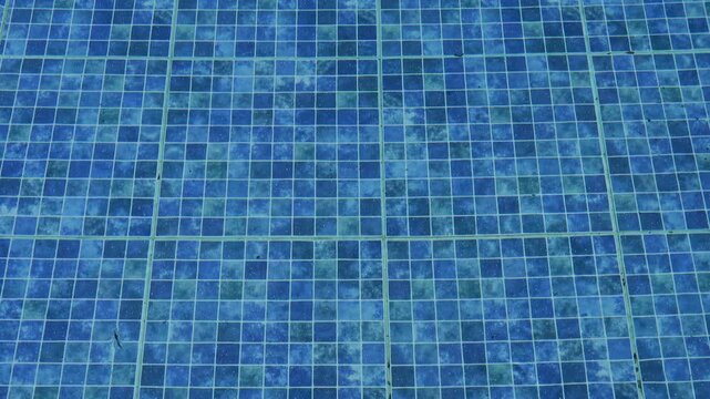 Top view of surface of the clear water and blue tile pattern in swimming pool. Summer concept, symbol of relaxation and vacation mood.