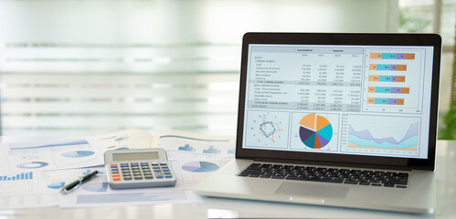 Financial graph showing a comparative analysis of business growth .with annual financial statement report and calculator on desk with copy space.