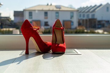Red ladies pumps on the floor in front of a window
