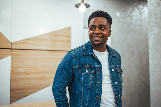 Smiling Young Man Wearing a Denim Jacket in a Modern Indoor Setting