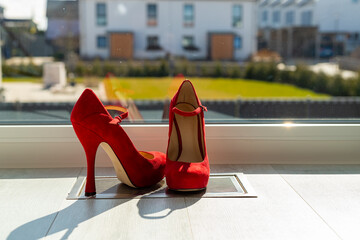 Red ladies pumps on the floor in front of a window