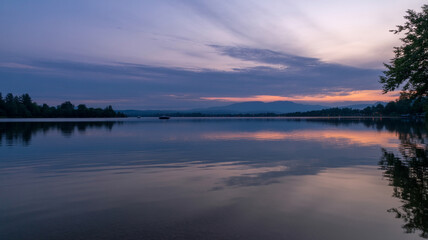 Obraz premium Tranquil lake scenery reflecting vibrant sunset colors with a calm water surface and beautiful clouds