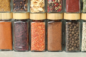 Many different aromatic spices in jars on table indoors, closeup