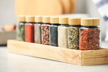 Different aromatic spices in jars on light table, closeup