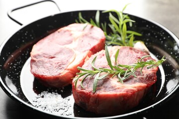 Pieces of raw beef meat and spices in baking dish on table, closeup