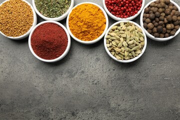 Different aromatic spices on grey table, flat lay. Space for text