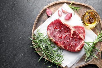 Piece of raw beef meat and spices on black table, top view. Space for text