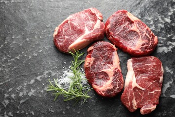 Pieces of raw beef meat and spices on dark table, flat lay. Space for text
