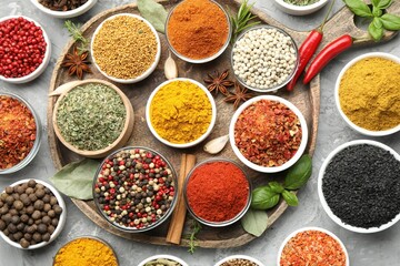 Different aromatic spices in bowls on grey table, flat lay
