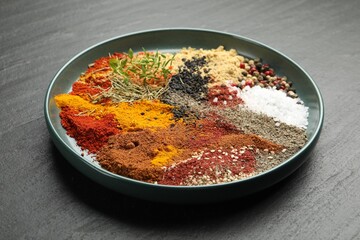 Different aromatic spices on dark textured table, closeup