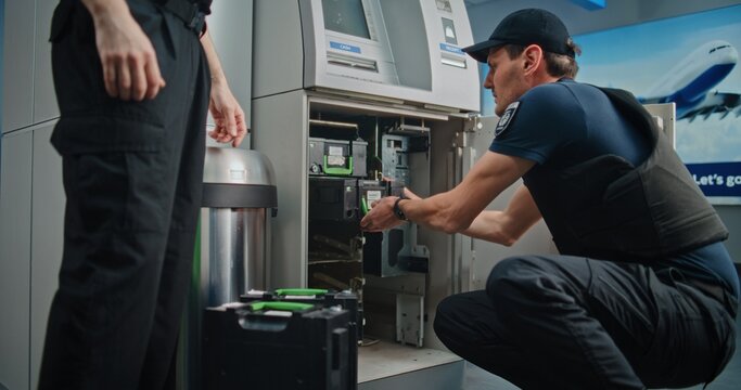 Professional Guards in Uniforms Performing ATM Encashment Procedure in Airport Terminal, Changing Cash Cassettes, Servicing Cash Machine. Cash-in-transit Operation for Safe Money Transportation.
