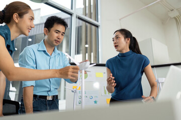 Obraz premium Sustainability Focus. Team members analyzing wind energy models in a creative workspace.