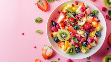 Bright fruit salad with kiwi banana and strawberry on pink background for healthy food photography setup