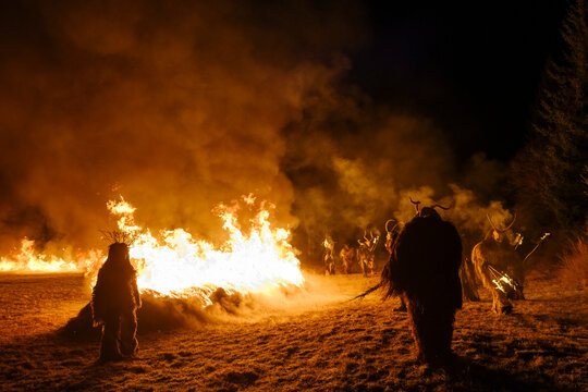 Night scene of Krampus figures in fur costumes standing near a large bonfire. Krampus and St Nicholas, 5 December in Tarvisio, Friuli Venezia Giulia, Julian Alps, Italy.