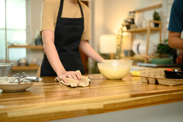Woman cleaning kitchen counter after mixing pancake batter at home
