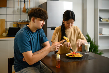 Happy couple enjoying homemade pancakes together at breakfast table