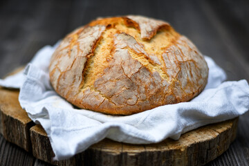 Appetizing cracked leavened sourdough bread with rough skin on a rustic wooden table. Healthy food photography