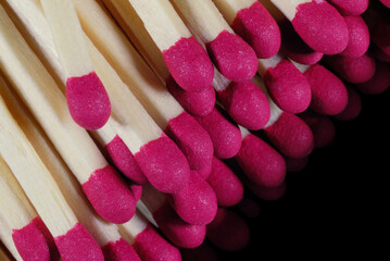wooden matches with red heads fall down on a black surface
