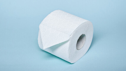 A clean roll of soft toilet paper sits on a light blue surface, emphasizing hygiene in the bathroom