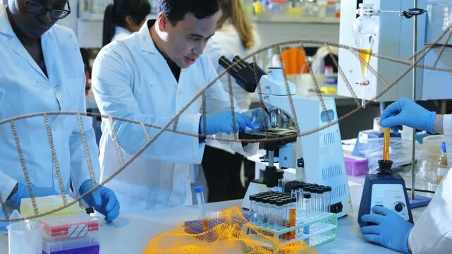 Lab scientists handling sample tubes in research with floating data graphs over microscope