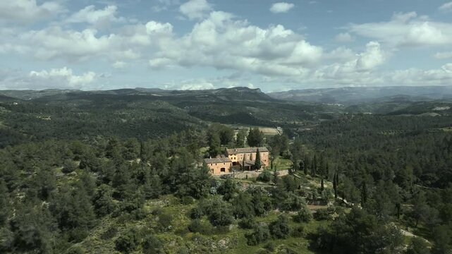 Aerial view of picturesque catalan hermitage mare de deu de pinyeres nestling amid serene el priorat landscape, revealing tranquil beauty under bright blue sky