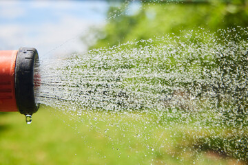 The flow of water from the sprinkler. Moisture for plants in the garden. Rain with your own hands
