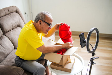 Excited Asian Senior Male Unboxing Delivery Package Recording Using Phone For Video Content