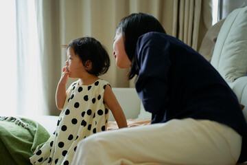 Young girl in polka dot dress shares a moment of curiosity with adult in cozy indoor setting on a...