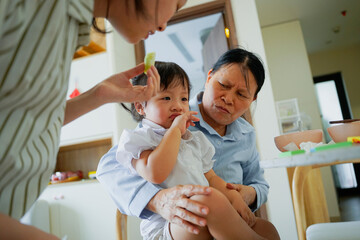 Family gathering in a cozy home with a child enjoying a snack while family members observe with care