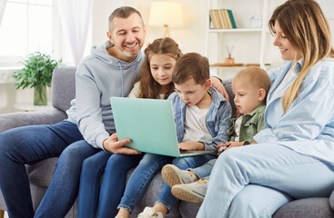 Happy big loving carefree family with kids gathered in cozy living room relaxing on sofa, use laptop watching cartoon, comedy, movie, educational program for kids online, stay at home at weekend