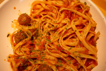 linguini spaghetti with meatballs and mediterranean sauce served on a white plate