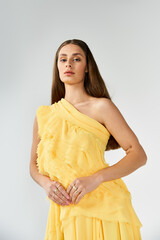 Beautiful woman in a vibrant yellow dress posing gracefully in a stylish indoor setting