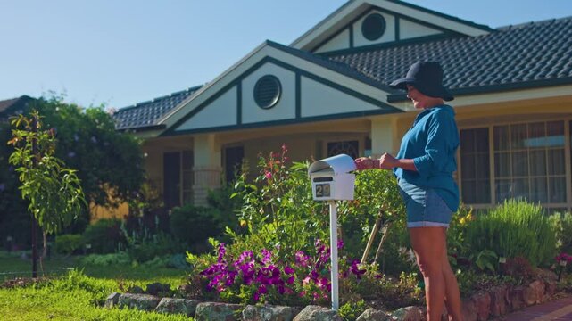 Woman checks mail in sunny Australian home garden