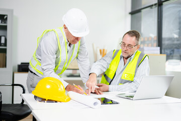 Engineers planning a construction project with blueprints, tablets, and hardhats. Concept of teamwork, architecture