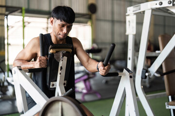 Fitness Commitment. Young man performing strength training on gym equipment for muscle enhancement.