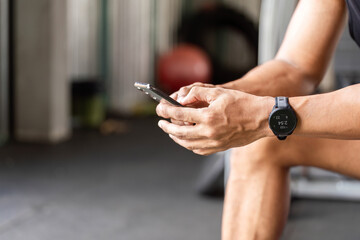 Fitness Technology. Athlete checking fitness app on smartphone during gym break.