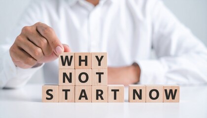 Businessman motivates with wooden blocks saying why not start now in modern office environment