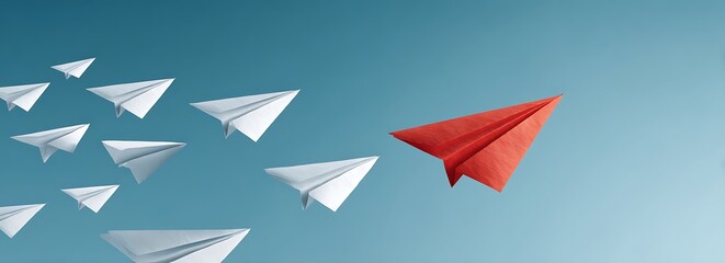 A single red paper airplane leads a flock of white ones against a serene blue sky symbolizing unique leadership and innovative thinking.