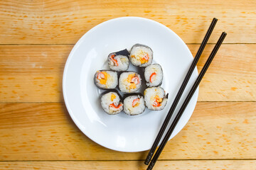 some pieces of sushi on a plate with chopsticks on a wooden table