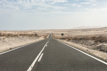 Road stretching through the arid landscape of Fuerteventura in daytime