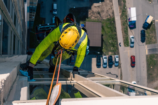 Rope access specialist washes the facade of a building