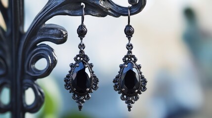 Elegant black gemstone drop earrings on ornate stand.