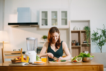 Smiling woman in a modern kitchen with fresh fruits, veggies, blender, and juice, embracing clean...