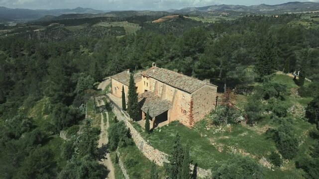 Aerial view of the catalan hermitage mare de deu de pinyeres, a historical sanctuary nestled amidst a serene landscape of lush greenery and rolling hills in el priorat, catalonia