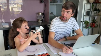 Little girl is trying to get the attention of her father who is working from home, she puts headphones on his head, he takes them off and explains that he is busy