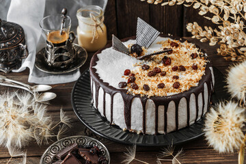 Delicious biscuit cake with cream, chocolate, nuts and dried fruits on wooden background. Sweets,...