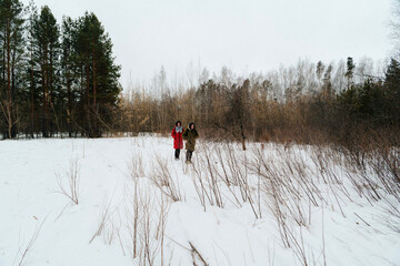 Friends enjoying a winter walk in a snowy landscape surrounded by bare trees in a serene setting