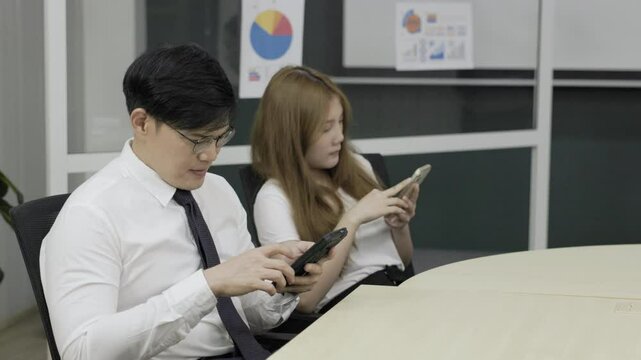 Lazy business team : Asian senior man supervisor gave the file to the team member who was using his mobile phone and was slacking off