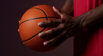 Fototapeta premium Close-up of a Person's Hands Holding a Basketball, Dark Background, Red Jersey